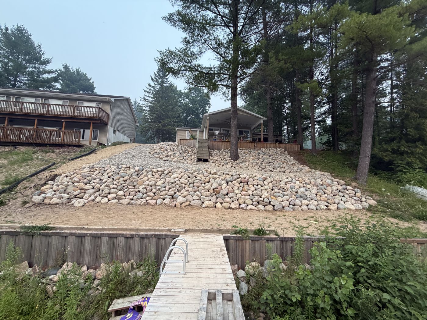Large river rock retaining slope built into a lakeside hillside, with a dock in the foreground